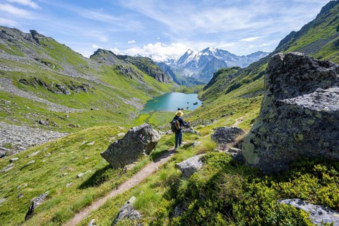 Mountaineer on hiking trail in picturesque mountain landscape, view of mountain lake Lac du Louvie