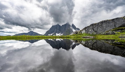 Small lake in mountain landscape, hike to Mount Barden, reflection with mountain peak Breidtind,