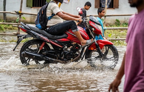 Commuters passing through a waterlogged street following heavy rainfall in Guwahati, India, on 1