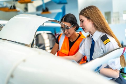 Female pilot and an aircraft maintenance engineer are inspecting the engine of a small plane in a