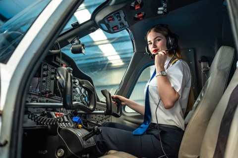 Confident female pilot preparing for takeoff, sitting in the cockpit of a small airplane, adjusting