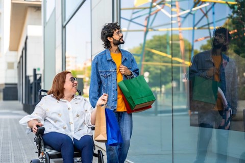 Smiling couple with shopping bags walking by a storefront window, enjoying a day of shopping