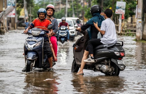 Commuters passing through a waterlogged street following heavy rainfall in Guwahati, India, on 1