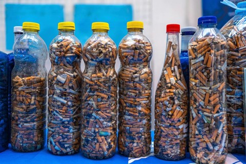 Plastic bottles filled with cigarette butts collected during a beach cleanup highlight