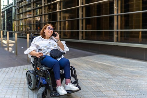 Happy businesswoman using a smartphone in a wheelchair, enjoying a moment of connectivity in the