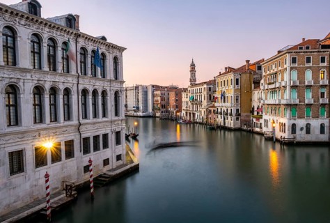 View of the Grand Canal with gondoliers at sunset, picturesque evening mood with illuminated
