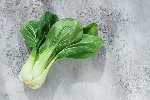 Fresh bok choy, laid out on a light gray surface, top view, natural light