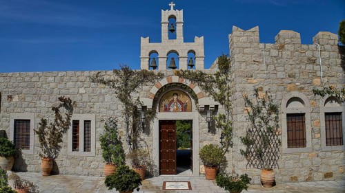 Church façade with bell tower and religious icon, surrounded by plants, woman's monastery,