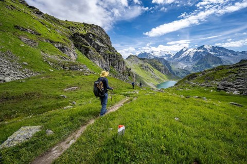 Mountaineer on hiking trail in mountain landscape, descent from Col du Louvie, view of Lac du