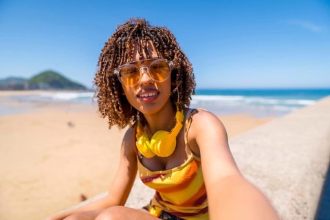 Tourist enjoying summer holidays at the beach, capturing a joyful selfie while soaking up the sun,
