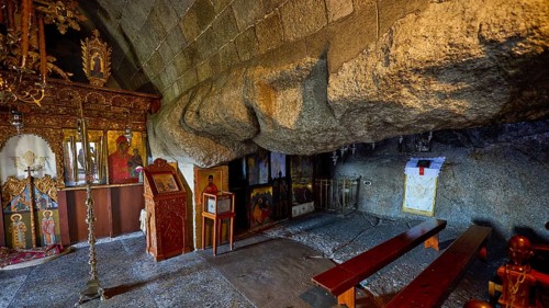 Church interior with icons and wooden benches set into a stone wall, Cave of St John, Grotto of