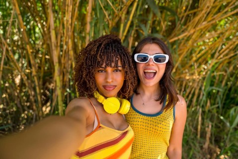 Two cheerful female friends capturing a joyful selfie while enjoying their vacation in a lush