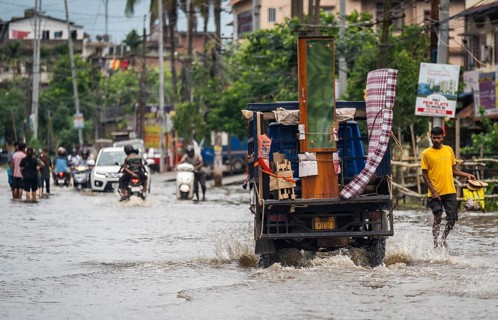 Commuters passing through a waterlogged street following heavy rainfall in Guwahati, India, on 1