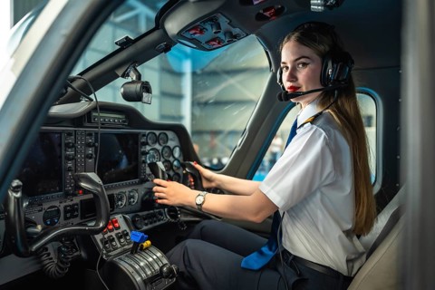Young woman pilot sitting in the cockpit of a modern aircraft, adjusting controls and preparing for