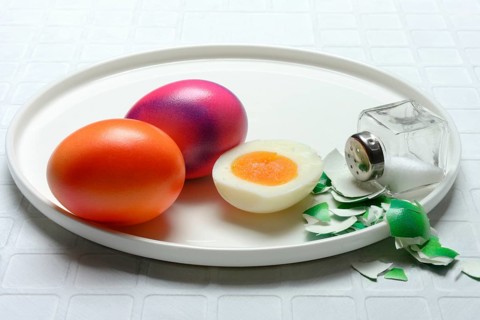 Easter eggs and salt shaker on plate, partially peeled