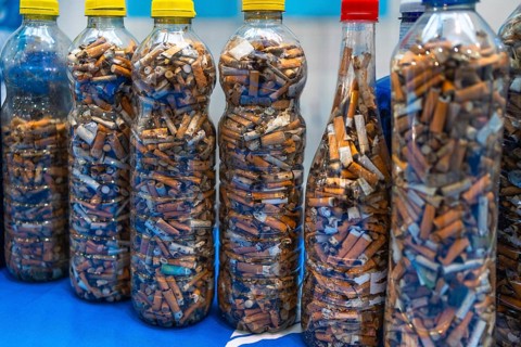 Plastic bottles filled with used cigarette butts highlight the environmental impact of smoking and