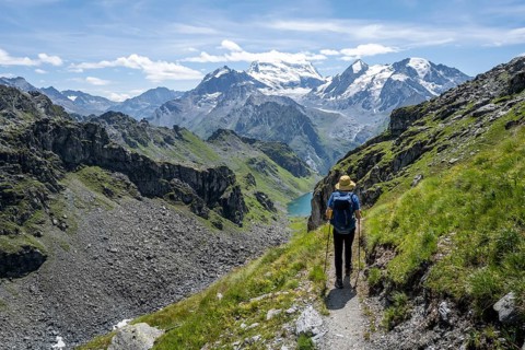 Mountaineer on hiking trail in mountain landscape, descent at Col du Louvie, view of the summit of
