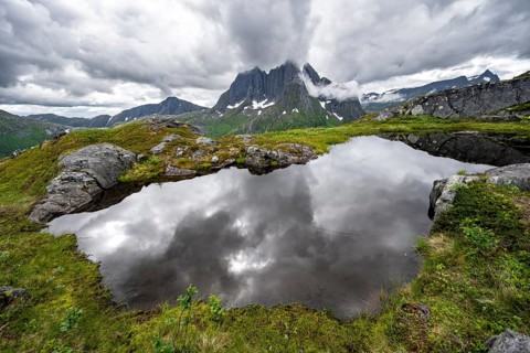 Small lake in mountain landscape, hike to Mount Barden, reflection with mountain peak Breidtind,