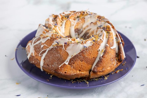 Marble bundt cake, cake with icing and edible flowers on a blue plate, light background