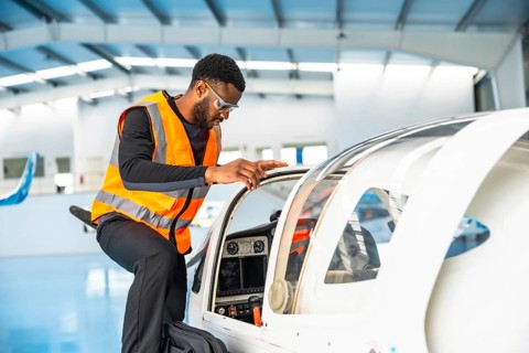 Aircraft maintenance engineer wearing safety glasses and a high visibility vest is inspecting the