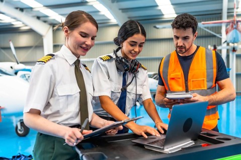 Aviation maintenance team working together, using a laptop and checklists for pre flight inspection