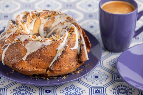 Marble bundt cake, cake with icing and edible flowers on a blue plate with coffee