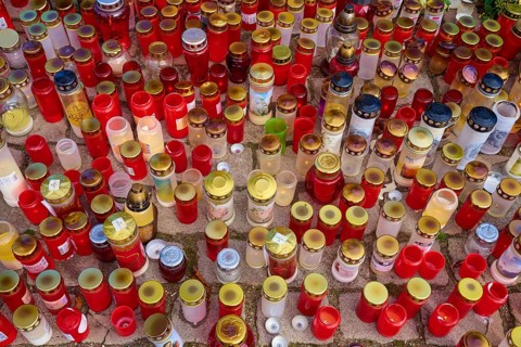 Many candles in different colours stand close together, creating a festive and contemplative