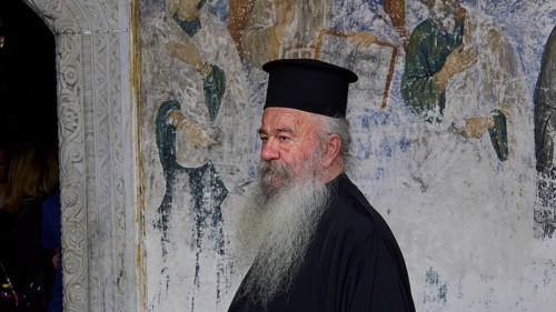 Priest in clerical garb in front of a religious mural, Monastery of St John the Theologian,