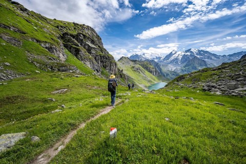 Mountaineer on hiking trail in mountain landscape, descent from Col du Louvie, view of Lac du