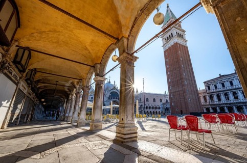 Chairs and tables of cafes, arcades at St Mark's Square in the morning light, St Mark's Basilica
