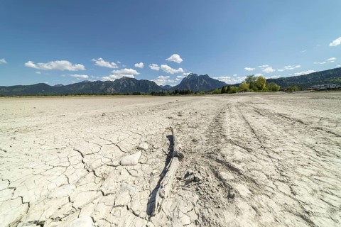 Cracked, dried out ground, waterless Forggensee in spring, behind it Tegelberg massif and Säuling,