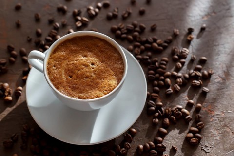 Cup of coffee cappuccino and coffee beans on the brown stone background