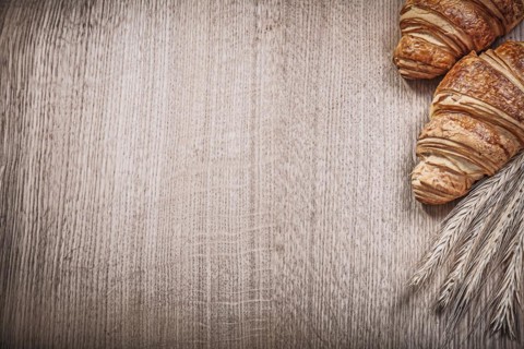 Golden wheat rye ears croissants on wooden board copyspace
