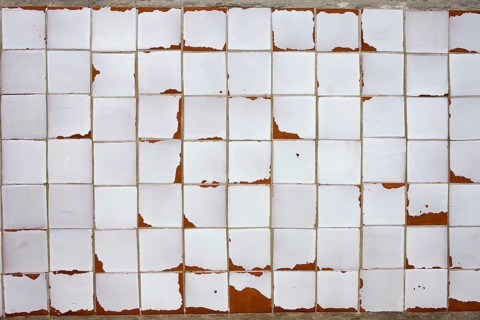 An old white obsolete and damaged tiled wall, good as a texture or background design element