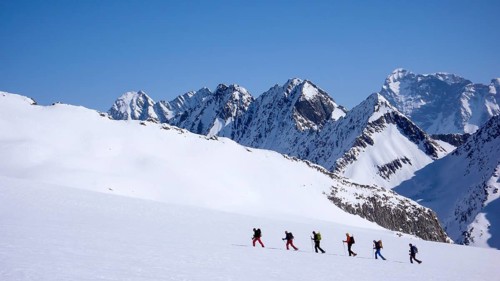 group of backcountry skiers crossing a glacier on their way to a high summit in the Alps of