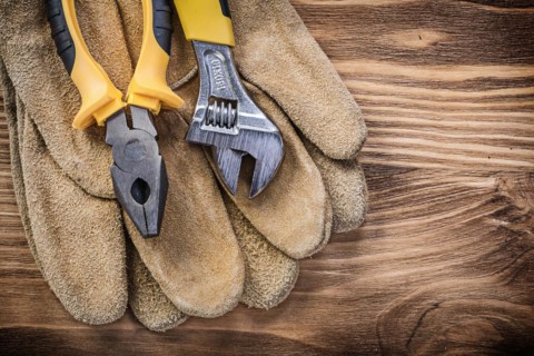 Leather safety gloves adjustable spanner pliers on wooden board construction concept