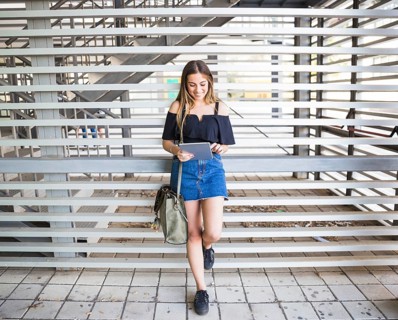 Young woman with bag using tablet university