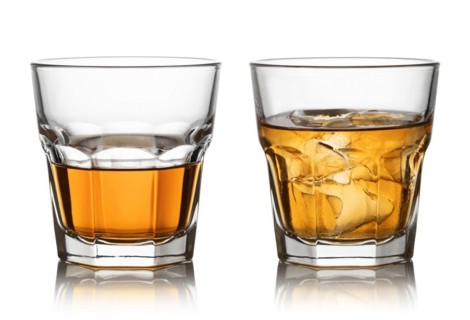 Glass of whisky and ice isolated white background
