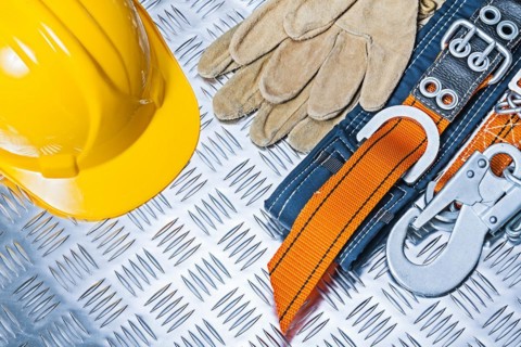 Yellow helmet, safety harness and gloves on corrugated metal plate