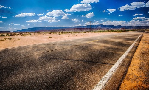 black asphalt highway with wind gust blowing red sand across inthe northern Arizona desert in the