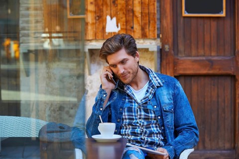 Young man with smartphone in an cafe outdoor sitting