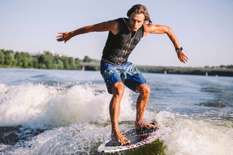 Active wakesurfer jumping on wake board down the river waves. Surfer on wave. Male athlete training