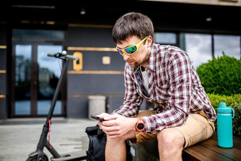 Individual urban environmental friendly transport electric kick scooter parked near man sitting on