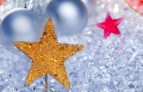 Christmas golden star symbol with silver baubles and red ribbon on ice