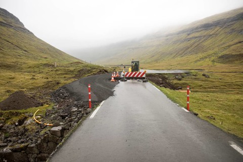Road construction site on the Faroe Islands with road block sign and digger, Streymoy, Faroe