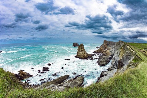 Powerful surf waves with a foam crest. Dramatic stormy sky. Cantabria Beaches, Portio Beach. Windy