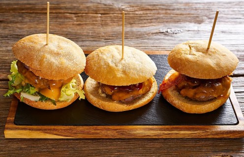 Burger in a row on a slate board and wood table
