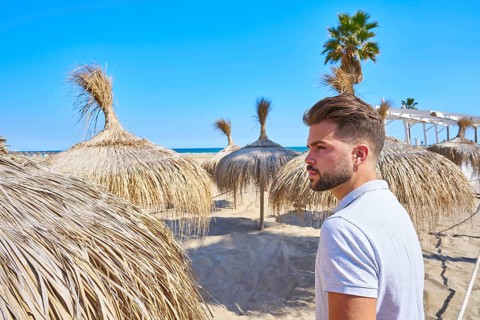 Young beard man in a beach with parasol at summer