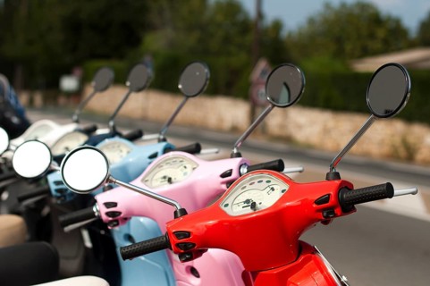 A line of mopeds/scooters on the city street