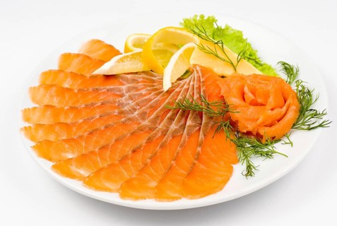 Sliced smoked salmon served with lemon and salmon rose